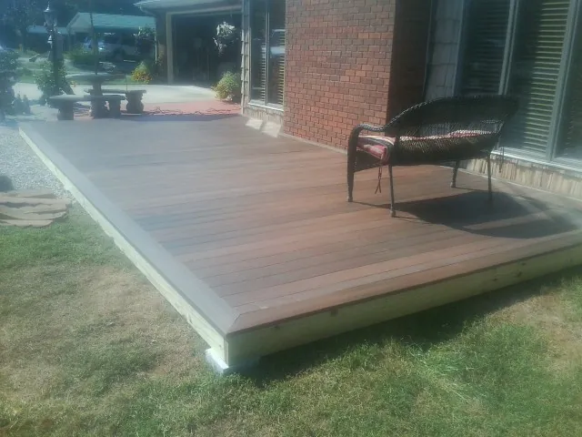 New wood deck and wicker chair beside a brick house in Afton