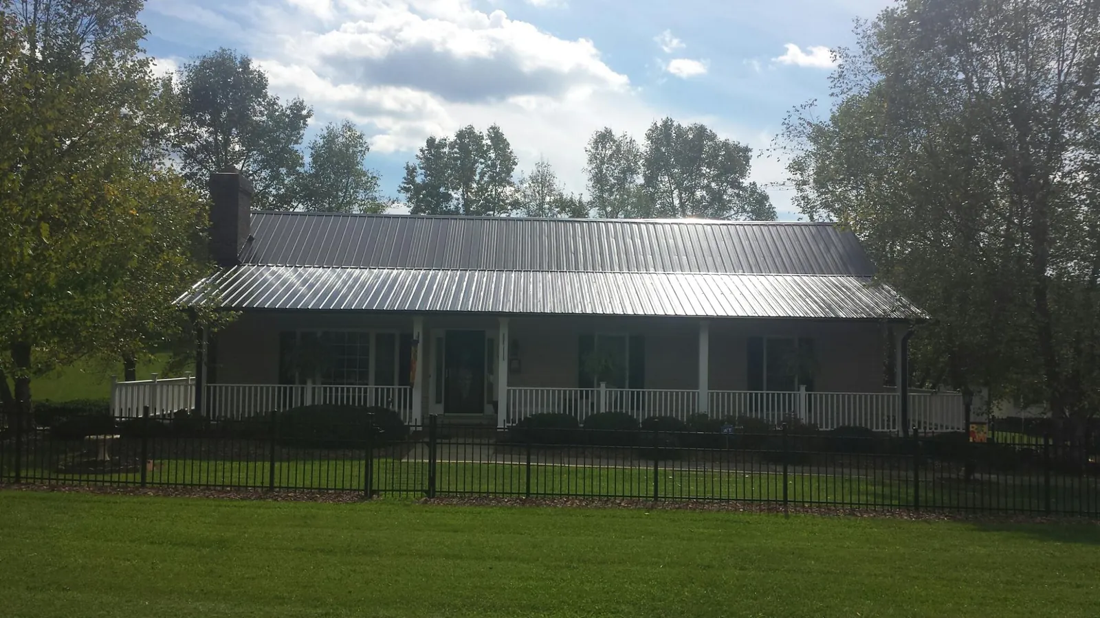 Gray metal roof on a brick ranch with a full width front porch — Gutter Guard Installation work by our crew in Afton